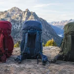 The best backpacking backpacks lined up on a rock ledge at a mountain pass