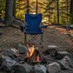 Camping chairs arranged around a fire ring at a forest campsite at golden hour