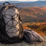 Grey hiking daypack on a granite boulder above a golden autumn valley