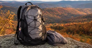 Grey hiking daypack on a granite boulder above a golden autumn valley