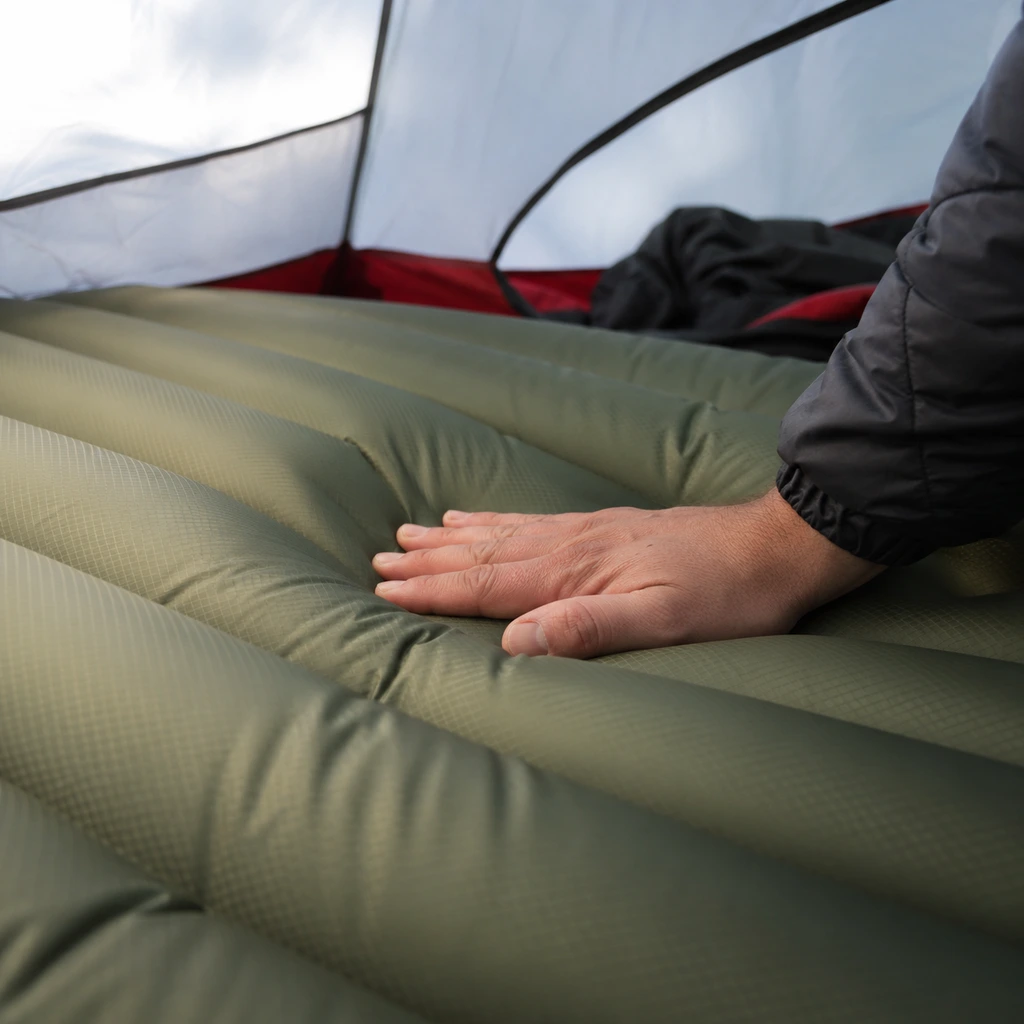 Testing one of the best sleeping pads for camping by pressing down on the inflated surface