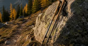 Cork grip trekking poles leaning against a granite boulder on an autumn mountain trail