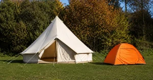 A cream canvas bell tent and an orange nylon dome tent pitched side by side