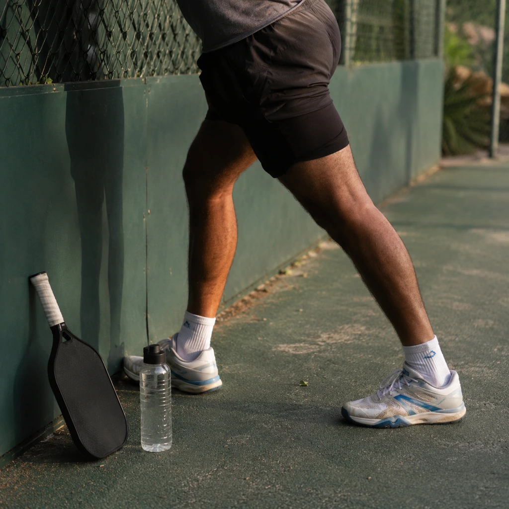 Calf stretch against the court fence after a pickleball session