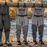 The best fishing waders hung on a rail beside an autumn river