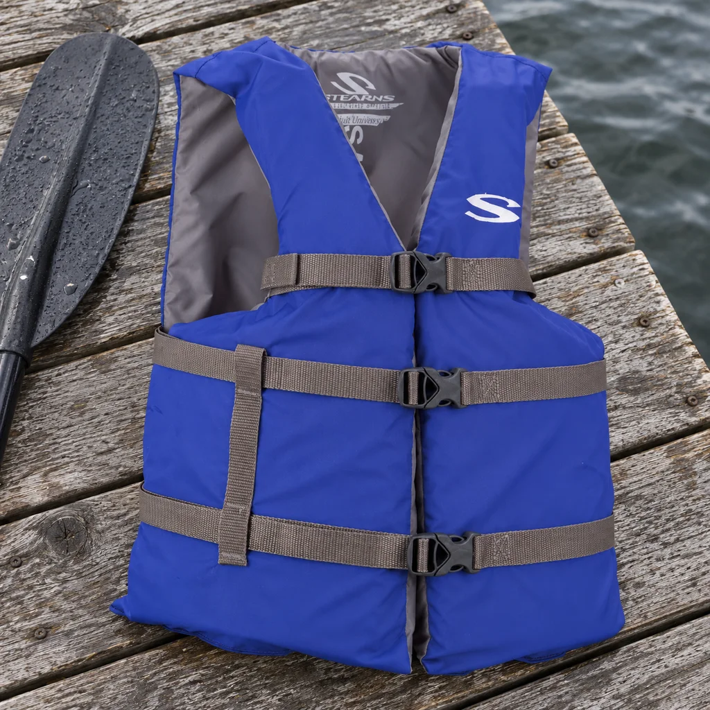 Stearns adult life vest laid flat on weathered dock boards beside a paddle