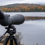 The best spotting scopes, a scope on a tripod at the edge of an autumn lake