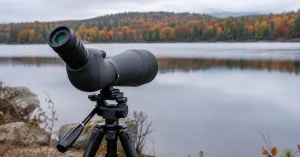 The best spotting scopes, a scope on a tripod at the edge of an autumn lake