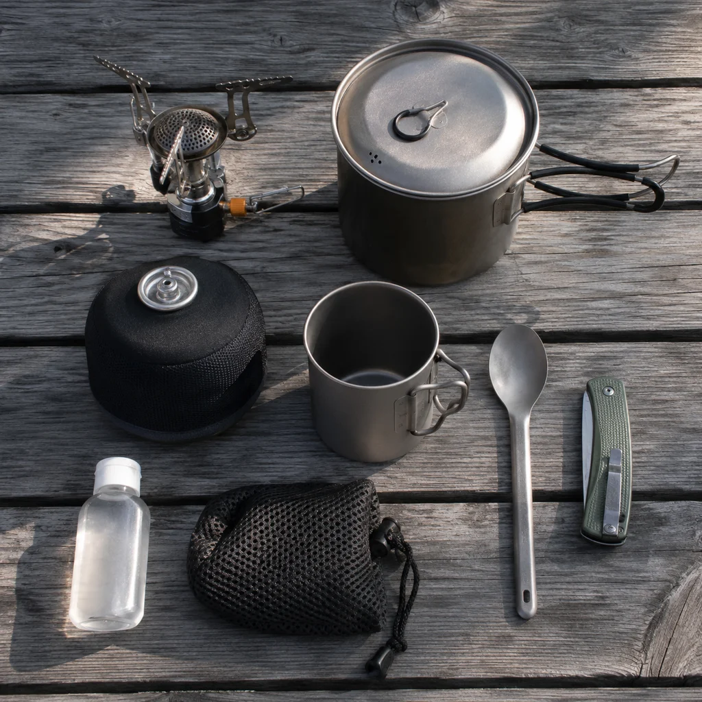 Flat lay of camp cooking kit with stove, pot, mug, spoon and fuel canister