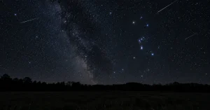 Orionid meteor shower over a dark rural field with Orion and meteor streaks